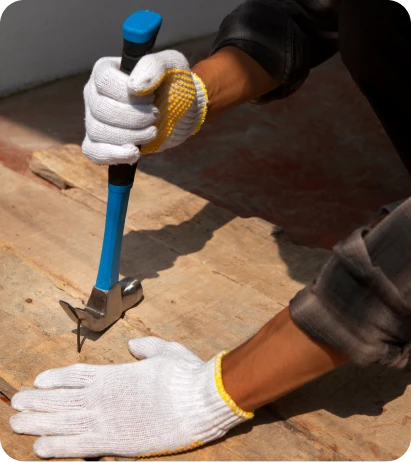 Reparacion de Goteras 4 Manos de trabajador con guantes golpeando un clavo en una tabla de madera con un martillo azul, en un proyecto de construcción