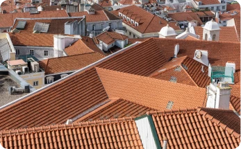 Vista aérea de varios tejados de tejas rojas en una zona urbana con edificios de diferentes tamaños y estilos