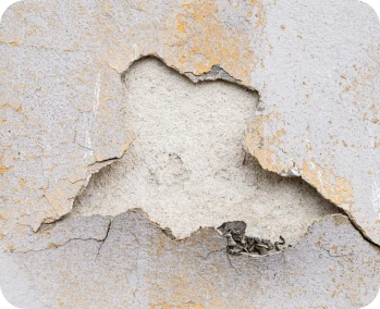 Reparacion de Humedades 3 Pared con yeso agrietado y desprendido, mostrando una sección de superficie expuesta debido al deterioro y falta de mantenimiento