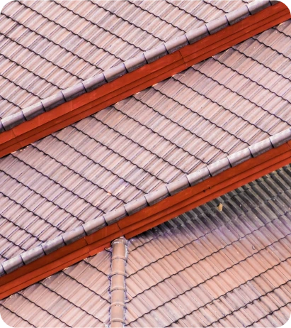 Reformas Integrales 9 Tejados de tejas grises con bordes rojos, mostrando un diseño geométrico en niveles de un edificio moderno visto desde arriba